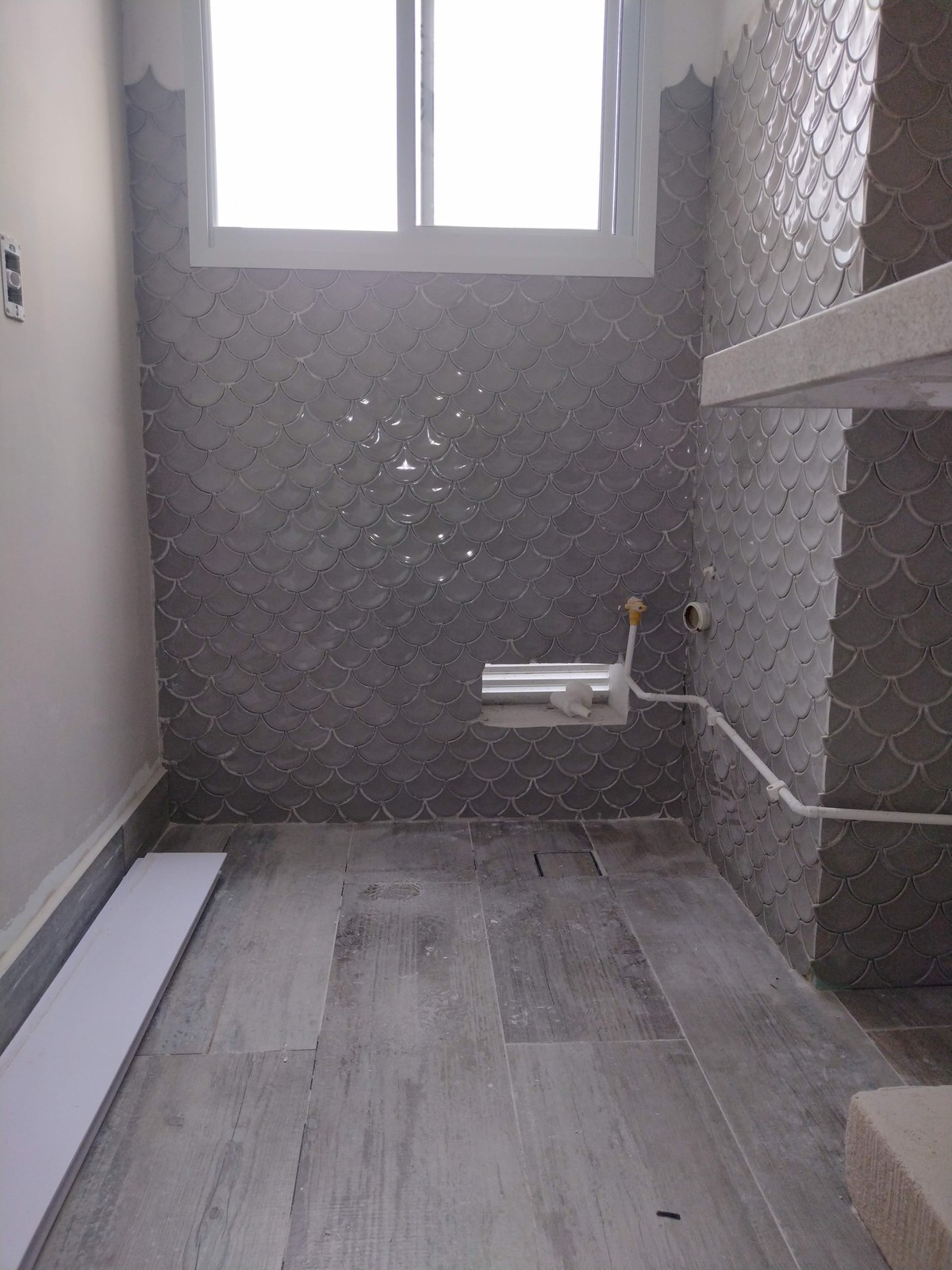 Banheiro reformado com revestimento em escama vidrada cinza e piso porcelanato amadeirado