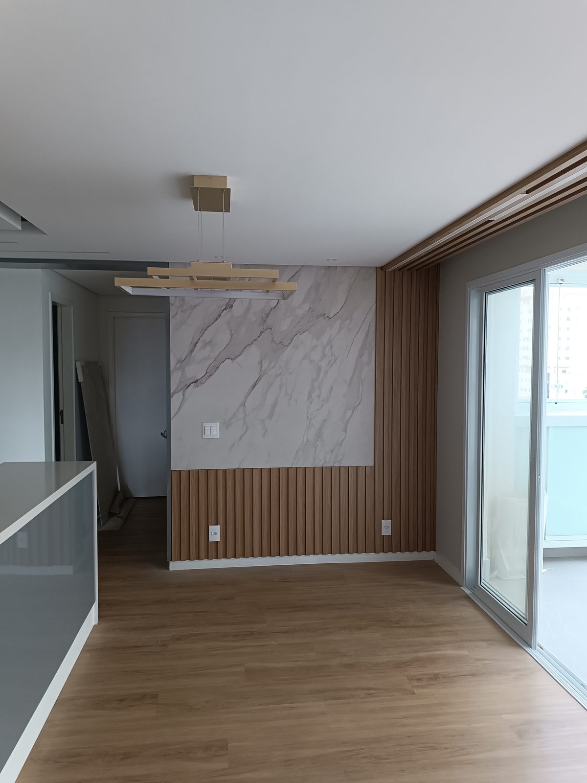 Living reformado pela Barreto Prime: painel em porcelanato marmorizado, ripado de madeira, iluminação em LED e piso amadeirado