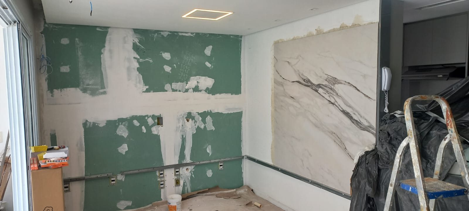 Fase 1: Sala em obra — drywall e primeiro painel de porcelanato marmorizado